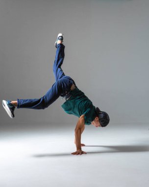 Havalı bir break dansçı gri arka planda elleri üstünde dans eder. Breakdance dersleri