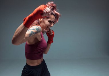 Atletik kız boks antrenmanları gri arka planda izole edilmiş bandajlarla yapılıyor. Kadınların spor ve motivasyon konsepti