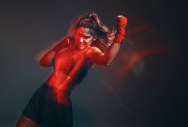 Boks bandajlı havalı kadın boksör stüdyoda kırmızı ışıkta tren kullanıyor. Karışık dövüş sanatları. Uzun pozlu çekim