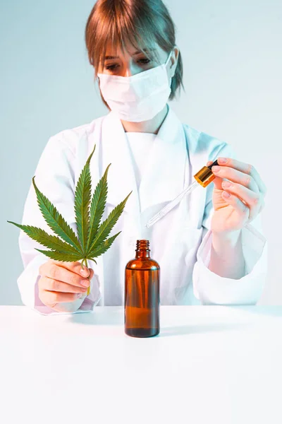 Femme scientifique avec une feuille de cannabis, une pipette et une bouteille d'huile de cannabis développant des produits du chanvre — Photo