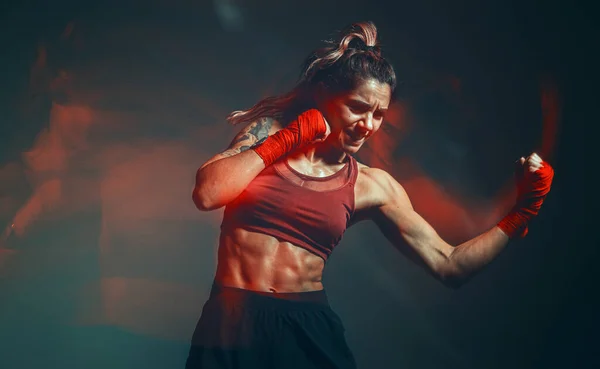 Cool combattente femminile in boxe bendaggi treni in studio in luce rossa al neon. Arti marziali miste. Colpo a lunga esposizione — Foto Stock
