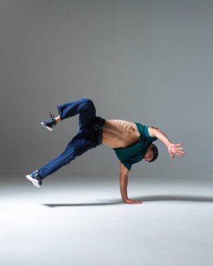 Stüdyoda dans eden havalı break dansçı. Gri arka planda fotokopi alanı ile izole edilmiş. Dans okulu posteri