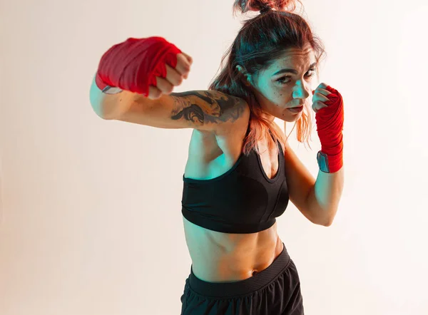 Uma boxeadora feminina com ligaduras nas mãos faz um golpe de mão e cotovelo.. — Fotografia de Stock