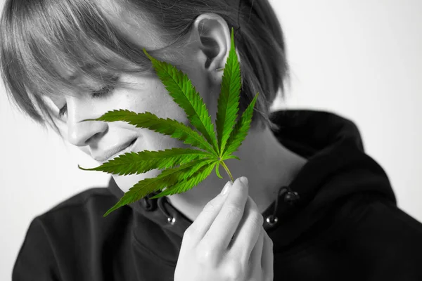 Potret hitam dan putih gadis muda tersenyum menutupi wajahnya dengan daun rami hijau — Stok Foto