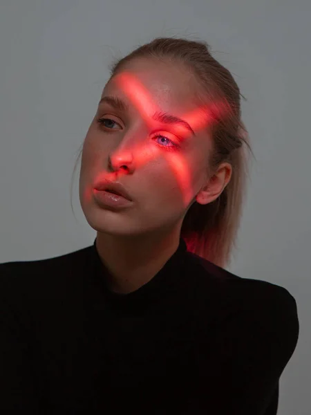 Gyönyörű fiatal lány, keresztalakú piros fénnyel a szemén. Kreatív női portré — Stock Fotó