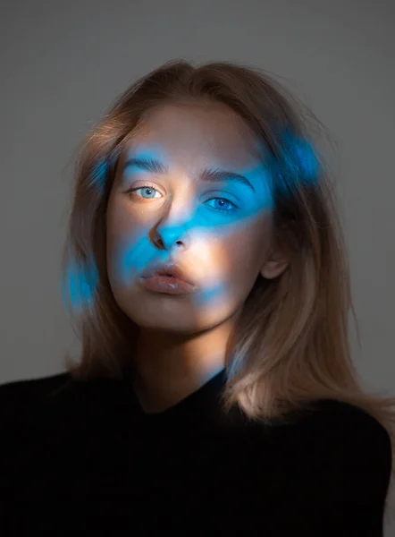 Studio portrét mladé dívky s skvrnami modrého světla na její tváři — Stock fotografie