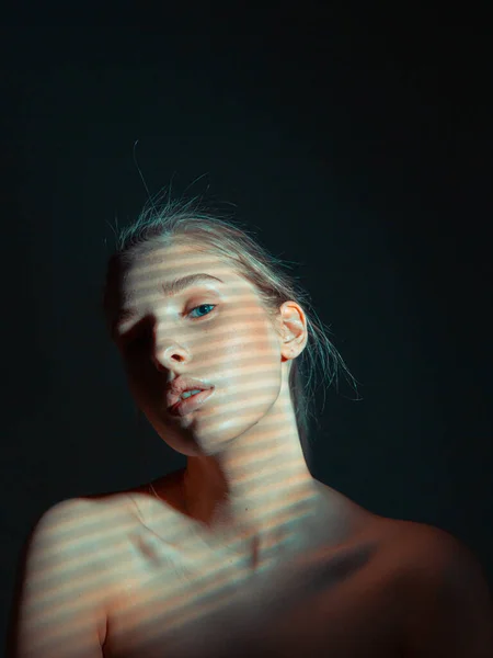 Záhadný portrét mladé dívky s nahými rameny a stínovým vzorem na kůži ve studiu na černém pozadí — Stock fotografie