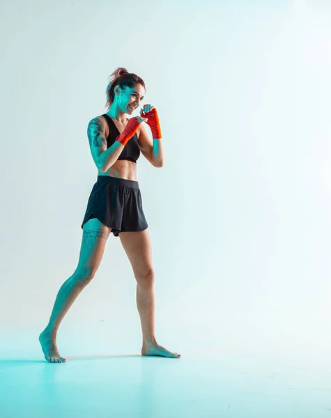 Menina sorridente atlética em sportswear elegante posando em estúdio isolado em néon. Cartaz de artes marciais mistas — Fotografia de Stock