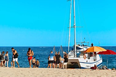 Lloret de mar, İspanya - 11 Temmuz 2019: Sahilde Yat. Erkekler ve kızlar denizin arka planında.