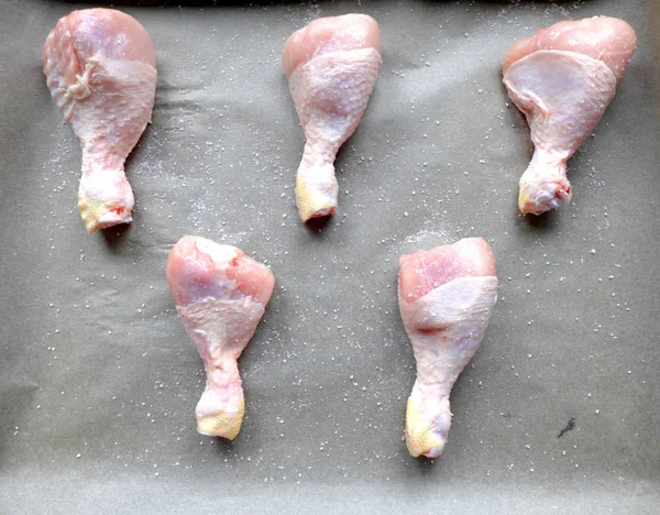 Patas de pollo crudas preparadas para cocinar en el horno en la bandeja para hornear y papel de respaldo con sal . — Foto de Stock