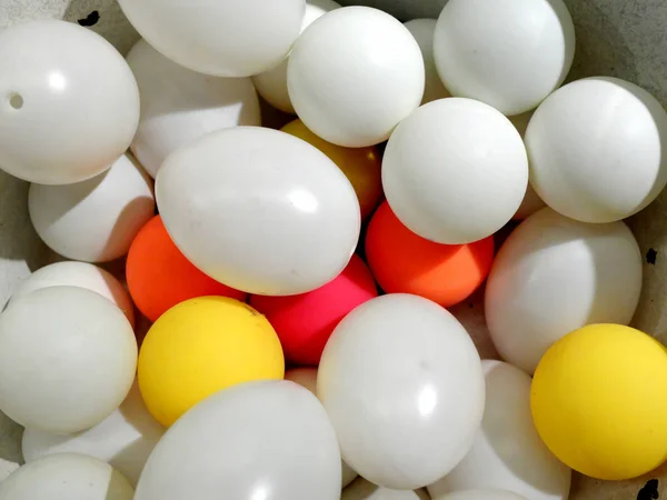 White plastic eggs and balls of different color laying together. — Stock Photo, Image
