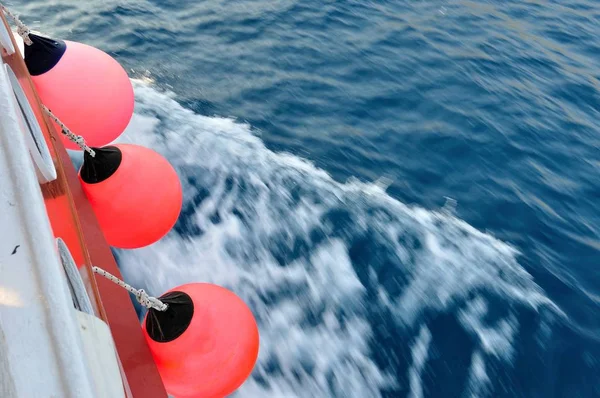 Red buoy on body of moving ship — Stock Photo, Image