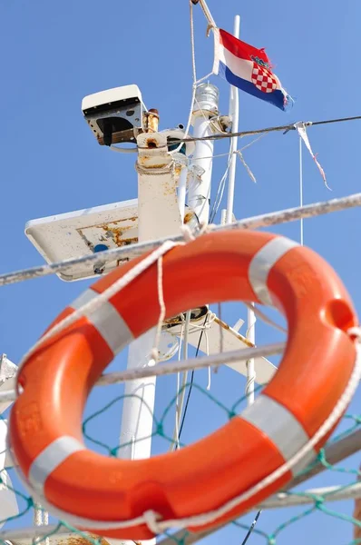 Апельсиновый спасательный буй висит на корабле с хорватским флагом — стоковое фото