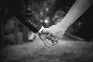 Genç evli bir çift, gelin ve damat, düğün gününde el ele tutuşuyorlar. Seçici odaklı düğün teması. Sığ DOF. Matt film efekti.