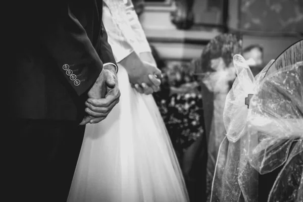 結婚式の間に教会で新郎新婦の手を握りしめました マットフィルム効果と黒と白の写真 — ストック写真