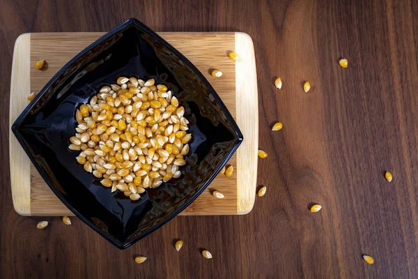 Tahta masada çiğ mısır tohumlarıyla dolu bir kase.