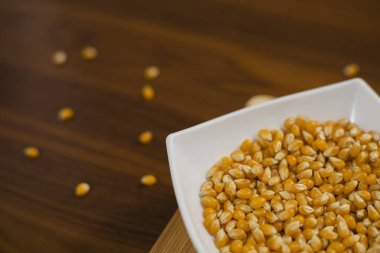 Tahta masada çiğ mısır tohumlarıyla dolu bir kase.