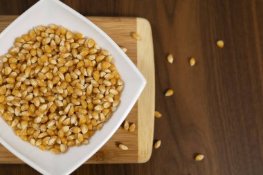 Tahta masada çiğ mısır tohumlarıyla dolu bir kase.