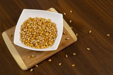 Tahta masada çiğ mısır tohumlarıyla dolu bir kase.