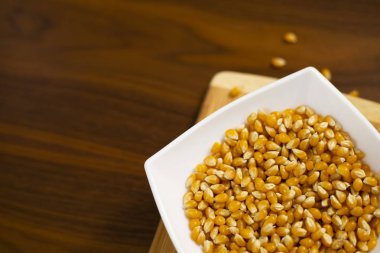 Tahta masada çiğ mısır tohumlarıyla dolu bir kase.