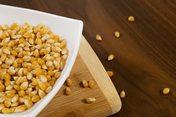 Tahta masada çiğ mısır tohumlarıyla dolu bir kase.