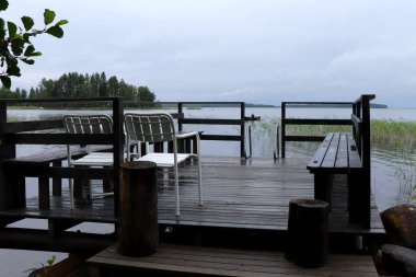 Yağmur, Finlandiya, Saimaa Gölü 'nde sandalye ve banklarla kaplıydı. Genç bir çocuk bulutlu bir günde tekneyle denizde kürek çekiyor.. 