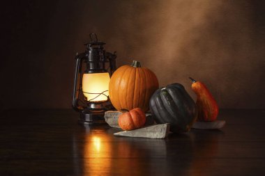 Balkabağı ve kabağın yanındaki tahta masada fener..