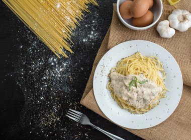 Ahşap masa arka plan üzerinde beyaz plaka spagetti cabonara, üst görünümü