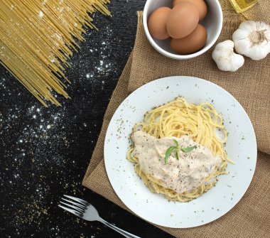 Ahşap masa arka plan üzerinde beyaz plaka spagetti cabonara, üst görünümü