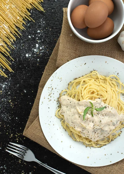 Ahşap masa arka plan üzerinde beyaz plaka spagetti cabonara, üst görünümü
