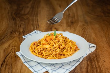 Ahşap bir arka plan üzerinde beyaz bir tabaktabak domates soslu spagetti