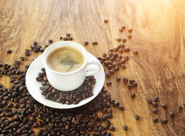 Kahve fincanı ve kavrulmuş kahve çekirdekleri. ahşap arka plan üzerinde.