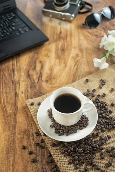film kamera, dizüstü bilgisayar ile Ahşap fotoğrafçı masa üzerinde kahve fincanı whit kahve çekirdeği