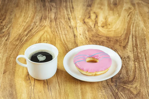 Café y rosquilla sobre mesa de madera . — Foto de Stock