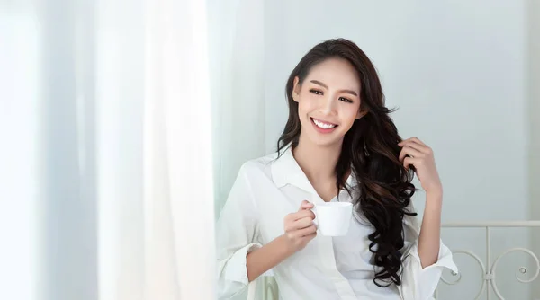 Beyaz bir gömlek ve kahve bardağı güzel bir Asyalı kadın 