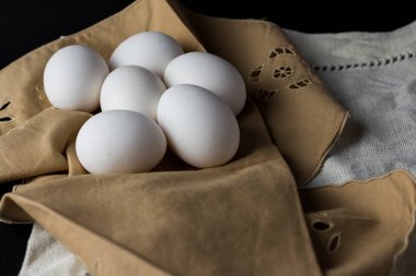 Kahverengi peçetedeki siyah arkaplanlı taze yumurtalar. Kopyalanacak alan 