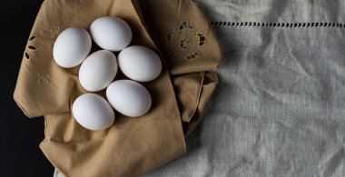 Kahverengi peçetedeki siyah arkaplanlı taze yumurtalar. Kopyalanacak alan 