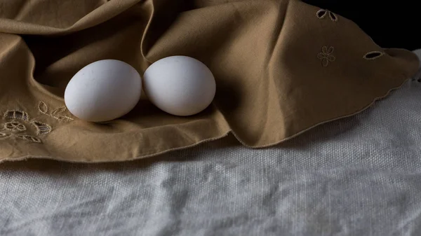 Fresh eggs in a brown cloth napkin with black background. Space to copy