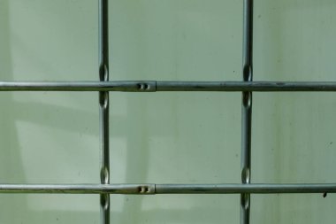 Plastik bir su tankının etrafındaki metal bir ızgarayı kapatın.