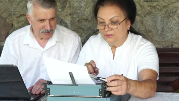 Зрелый мужчина работает ноутбук женщина на пишущей машинке — стоковое видео
