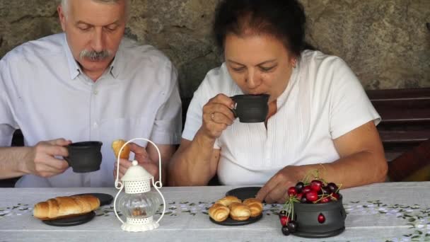 Oude man met vrouw genieten van thee met croissants — Stockvideo