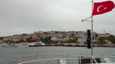 kıyıya iskeleye doğru rüzgar Türk bayrağı dalgaları ile feribot tekne yelken. Istanbul Boğazı Marmara Denizi üzerinde atış. kıyı şeridi için yerleştirme. sisli bulutlu hava