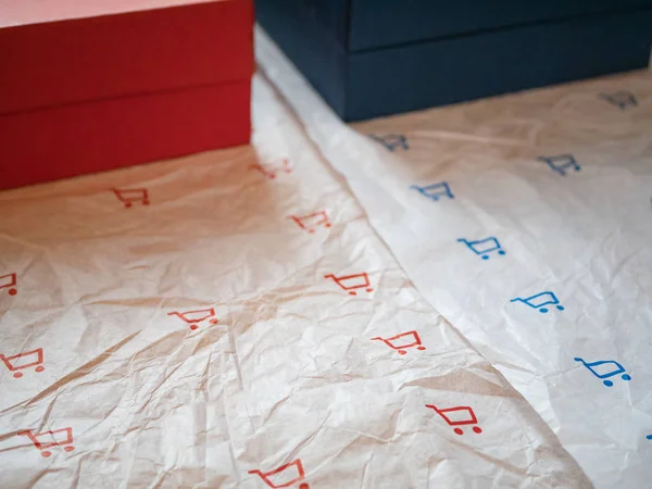 two types of wrapping paper with shopping cart symbol and two card boxes with matching red and blue colors. closeup shot