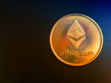 arka plan olarak siyah metal yüzeyinde bir ethereum altın madeni para. düşük anahtar düz çekim yatıyordu