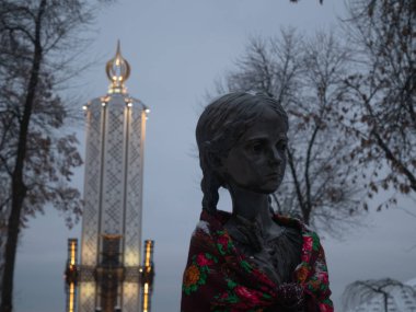 Buğday spikelet sembol Holodomor Ukrayna, Kiev, tutan küçük kız closeup Anıtı. tüm Rus Sovyet rejimi kurbanları anısına. Alacakaranlık günbatımı kış