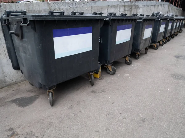 办公楼附近的一排黑色塑料垃圾容器 有空标签供复制空间 — 图库照片