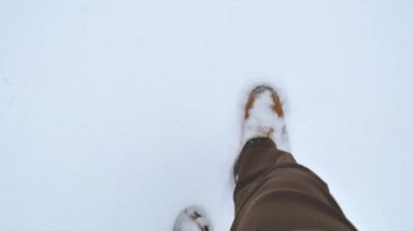adam büyük kış botlarının içinde adımları temiz el değmemiş beyaz karda yürür. Sadece ayak görünür. closeup pov 4k görüntüleri