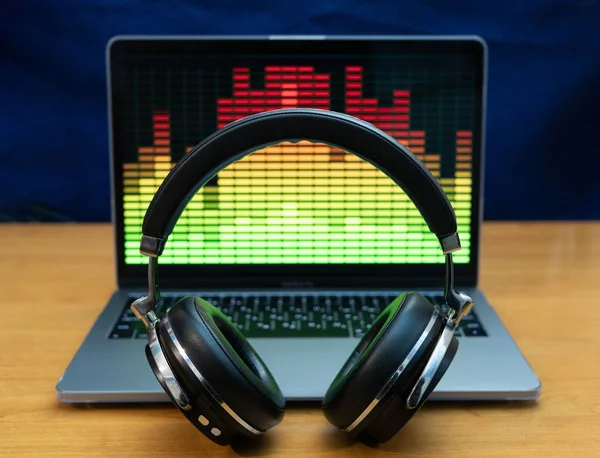 Studio kulaklık ile müzik çalar ekolayzır monitör dizüstü bilgisayar önünde dik duruyor. Açık yakın çekim ile arka plan bulanık vurdu