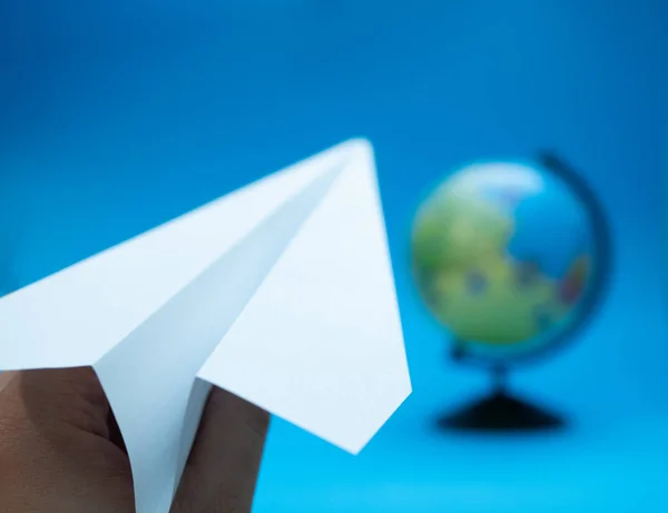 白色手工纸飞机与地球模糊的背景 飞行更多的旅行理念 有选择地聚焦于飞机最接近的部分 — 图库照片