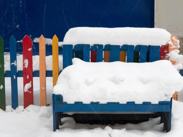 在巨大的雪堆下的木长凳特写镜头 生动多彩的户外拍摄在雪灾 — 图库照片